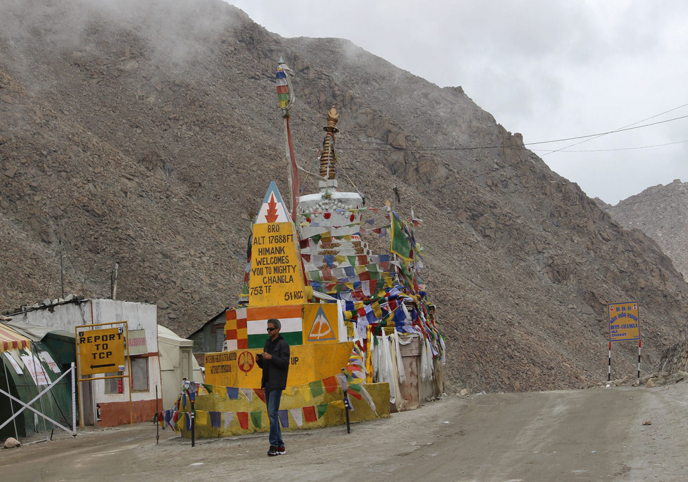 A man standing near a temple at Chang La Pass.